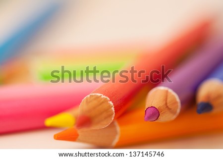 Bunch of multiple colored drawing pencils on a school desk, interior.