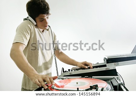 Young DJ playing and mixing music in a night club, with his headphones on isolated against a white background.