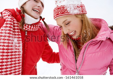 Close up portrait view of two joyful young women friends having fun and laughing while in a skiing holiday in a white snow  landscape lake with big joy expressions and excitement, outdoors.