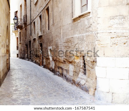 Tourist travel view of a narrow street in the old town of Palma de Mallorca with natural stone buildings and pedestrian stone road. Charming and characterful street and holiday destination.