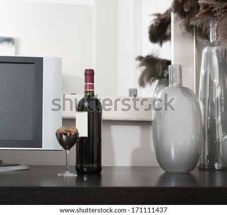 Still life view of a high technology room room with a flat screen tv and a full bottle of red wine with olives on a wooden chest in a luxury home. Elegant hotel bedroom interior with technology.