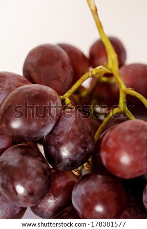 Still life close up detail view of a bunch of matured red wine grapes against a white background. Healthy diet and nutritious fruit foods.