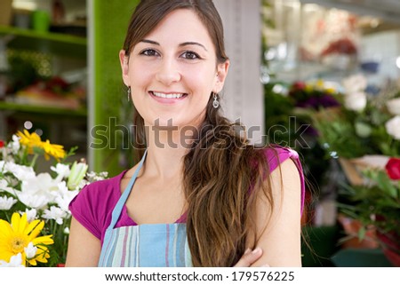 Close up portrait of a business woman florist working at her flower market shop, feeling proud standing with her arms crossed in front of her small business, outdoors. Business person.