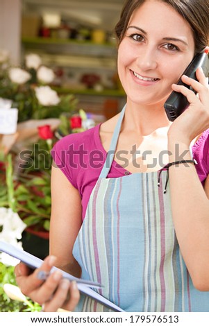 Close up portrait of a florist business woman working at her flower market store, using a phone to have a conversation and order stock. Business owner running a retail shop, outdoors.