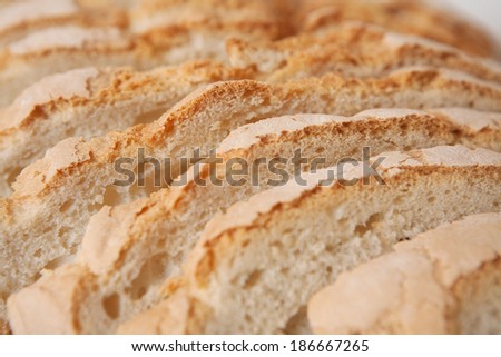 Macro close up detail of a home baked loaf of white bread with crunchy crust cut in slices with a golden color. Fresh food baking and cooking in home interior, objects.
