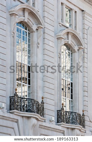 Close up still life detail view of an old stone building with intricate decorative detail in the city of London with large windows and reflective glass. Classic luxurious architecture background.