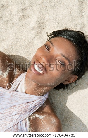Black and white view of an attractive african american black woman with a perfect body and skin, sunbathing and relaxing on a sandy beach during a summer holiday, outdoors. Healthy lifestyle travel.