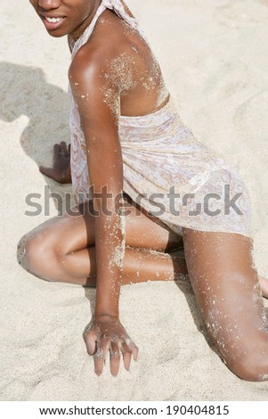Black and white view of an attractive african american black woman with a perfect body and skin, sunbathing and relaxing on a sandy beach during a summer holiday, outdoors. Healthy lifestyle travel.