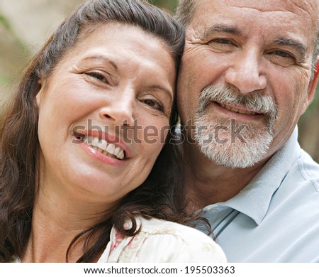 Close up portrait of a healthy and attractive senior couple relaxing on holiday, leaning on each other and being loving and close. Mature people enjoying romance and retirement, outdoors lifestyle.