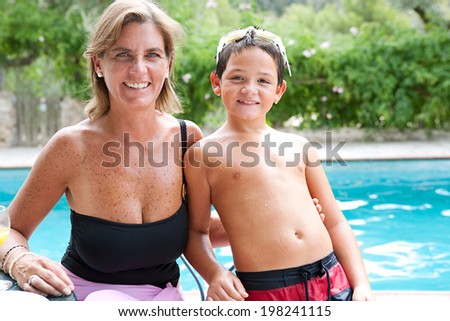 Close up portrait of a joyful mother and son enjoying a summer day together in a holiday home garden and swimming pool, smiling and being active. Vacation and relaxing family lifestyle, outdoors.