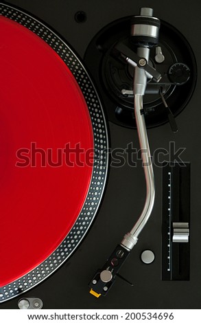Over head close up detail view of a record player with a red vinyl album, interior. Still life professional musical equipment objects.