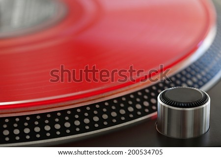Macro close up detail view of a red vinyl album on a professional dj turntable, interior. Still life background of professional musical equipment objects.