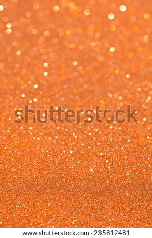 Abstract ochre orange glitter festive background texture with shining glitter stars. Full frame yellow color christmas detail with blurred areas. Artistic colorful background drop frame space.