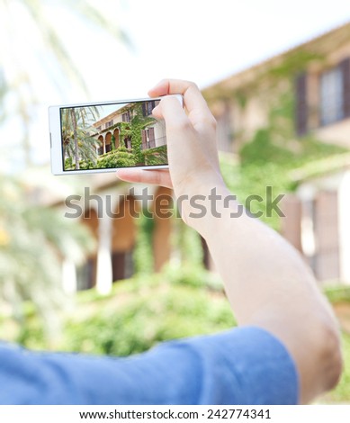 Detail view of a young woman hand holding a smartphone device up and taking photos of a monument visiting a destination city on holiday. Vacation travel technology lifestyle networking.