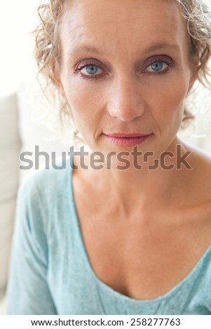 Aspirational close up beauty smiling portrait of an attractive mature healthy woman at home, being thoughtful and relaxing indoors. Home living and well being lifestyle.