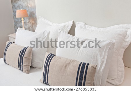 Still life home interior of double bed bedroom, stylish home with comfortable cushions and pillows, indoors. Design hotel room with a pattern wallpaper and elegant furnishings, aspirational lifestyle.