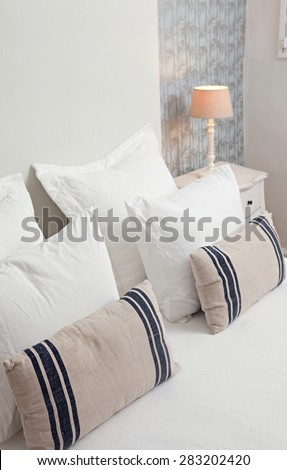 Still life view of a comfortable luxury home bedroom with pillows in a quality family home, interior design. Stylish bed in home room with a pattern wallpaper with nature details, indoors.