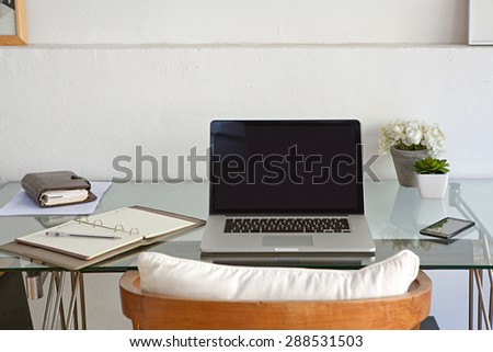 Still life view of a home office room with a laptop computer and a smart phone, house interior. Working from home technology in a home work desk, indoors. High technology lifestyle workplace.