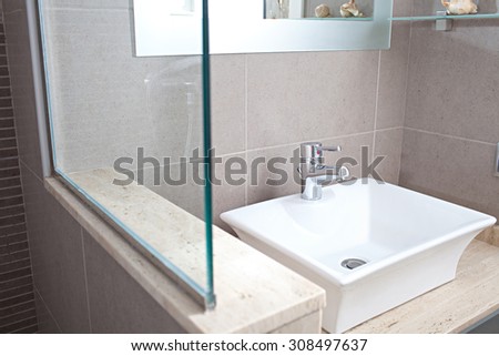Still life view of a new white sink with silver tap in a stylish bathroom in a quality design home, interior. Bath room with shower and basin in a hotel room, travel and aspirational lifestyle.