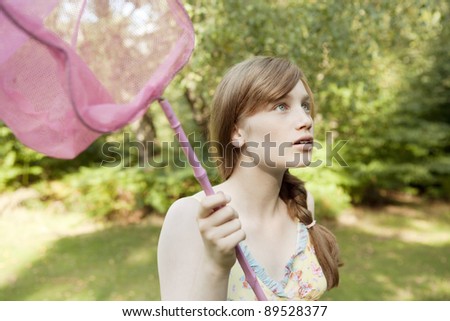 Teenage girl holding a butterfly net in the forest.