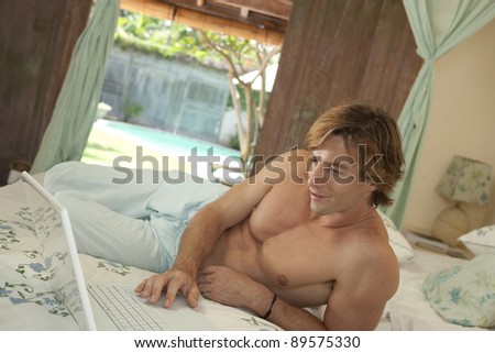Man using a laptop in his bedroom.
