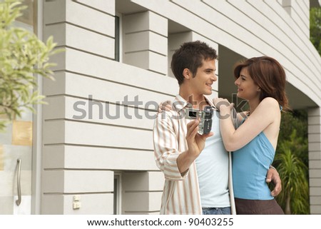 Young couple arriving at their new home and recording themselves at the house\'s entrance garden.