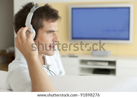 Young man listening to music with headphones at home.