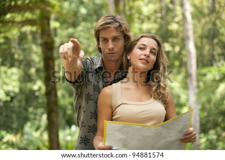 Couple reading a map in a tropical forest.
