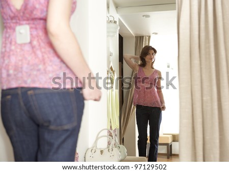 Young woman trying on an outfit in a fashion store fitting room.