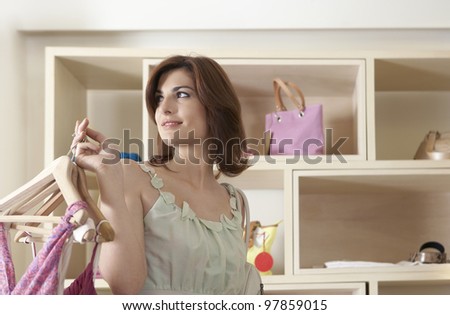 Sophisticated woman holding hangers with clothes in a store.