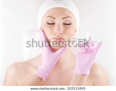 Beautiful woman gets an injection in her face isolated on white
