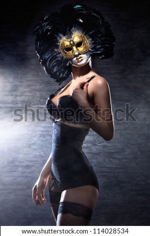Young attractive woman in mask over dark background