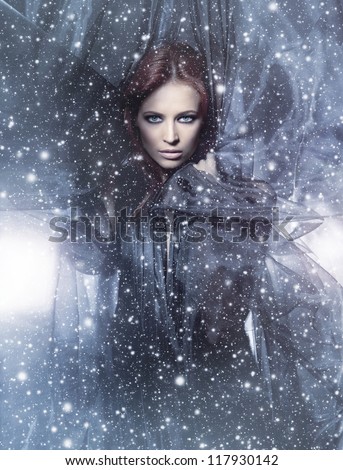 Fashion shoot of young attractive woman in blowing silk over the snowy background