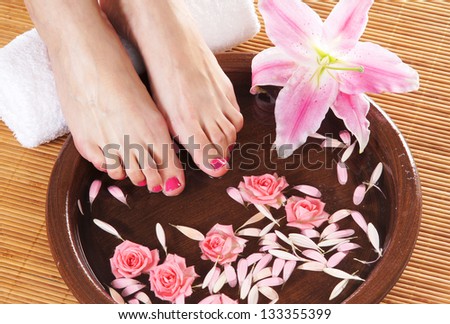 Spa background with a beautiful legs, flowers, petals and ceramic bowl