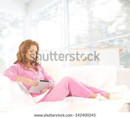 Young, beautiful and happy woman is reading in the home interior