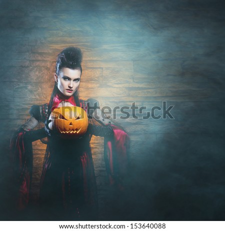 Beautiful, young and sexy female vampire over the smoky background. Halloween concept.