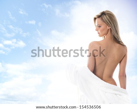 Young, beautiful and sexy blond woman in towel over the sky background