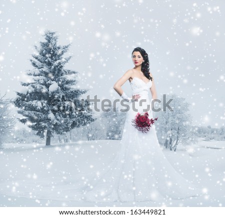 Young and beautiful bride with the flower bouquet in winter forest