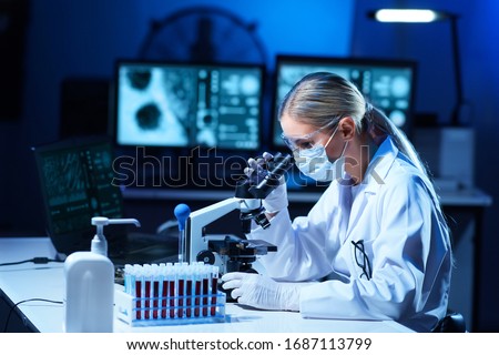 Female scientist working in modern lab. Doctor making microbiology research. Laboratory tools: microscope, test tubes, equipment. Coronavirus covid-19, bacteriology, virology, dna and health care.