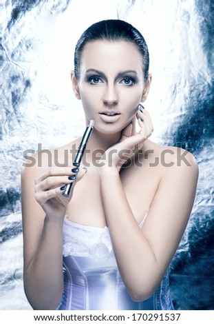 Glamour and bizarre portrait of young and beautiful woman with the electronic cigarette in creative winter style