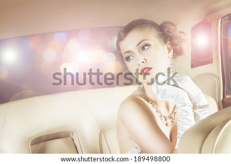 Beautiful and rich superstar girl sitting in a retro car