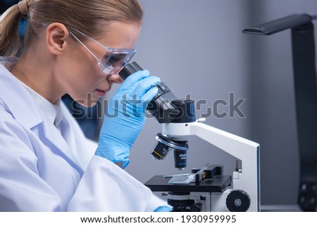 Professional female scientist is working on a vaccine in a scientific research laboratory. Genetic engineer workplace. Technology and science concept.