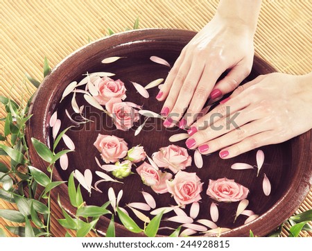 Hands, flowers, petals and ceramic bowl. Spa, recreation, manicure and skin care concept.