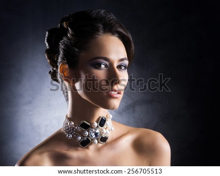 Young, beautiful and rich woman in jewels of platinum and stones over luxury background