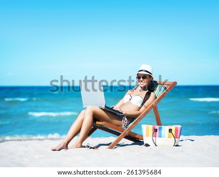 Young, beautiful, sporty and sexy woman with the notebook pc relaxing on the beach