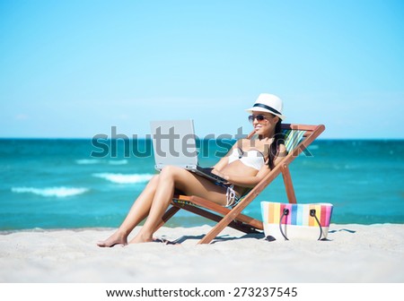 Young, beautiful, sporty and sexy woman with the notebook pc relaxing on the beach