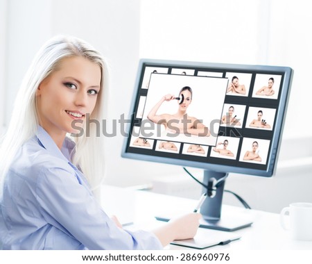 Young, attractive and confident woman working in office. Retoucher editing photos.