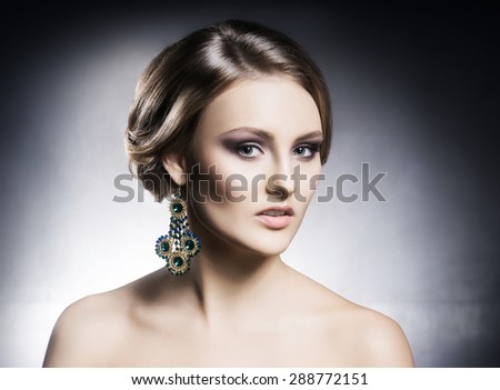 Young, beautiful and rich woman in jewels. Metal background