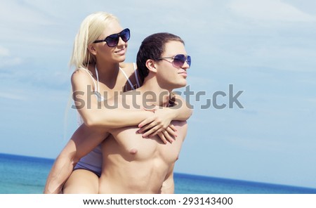 Handsome man and young beautiful woman hugging on a summer beach