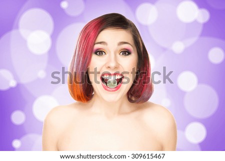 Beautiful girl with colored hair having a jelly in mouth on bubbly background.